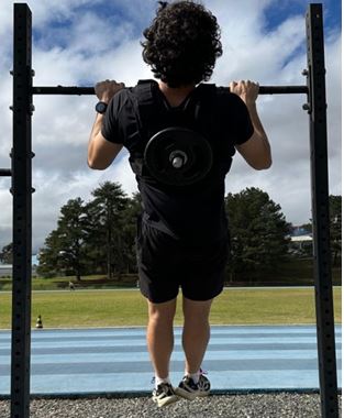 Figura 1. Execução do teste de 1RM na barra fixa utilizando colete de sobrecarga